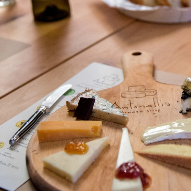 Wooden board with triangular slices of cheese topped with various jams