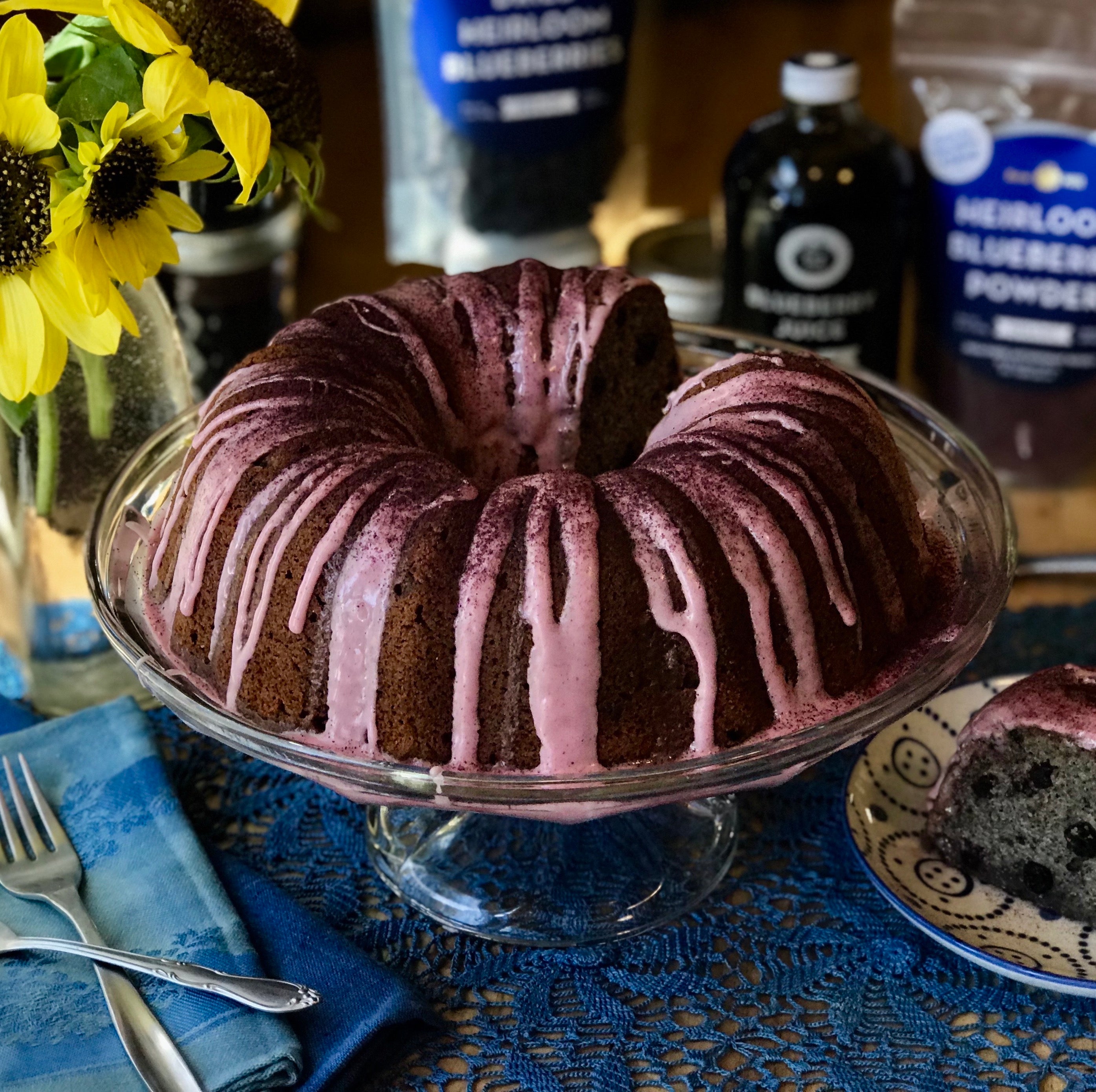 Bundt cake with blueberry icing, blueberry products and sunflowers in background