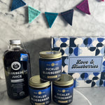 Pickled blueberries and blueberry juice on a marble surface with decorative elements.