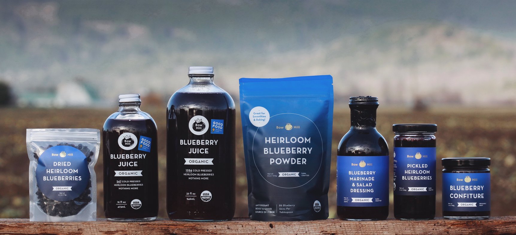 Blueberry product line displayed on wood in front of a field